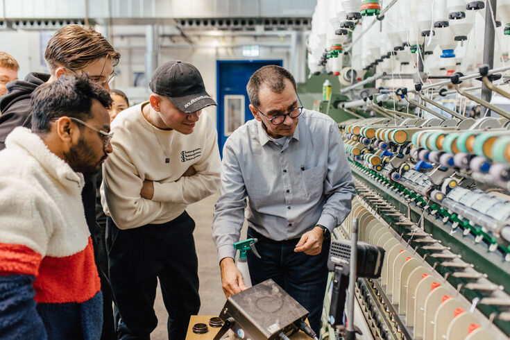 Professor erklärt Studierenden Spinnmaschine in der Maschinenhalle